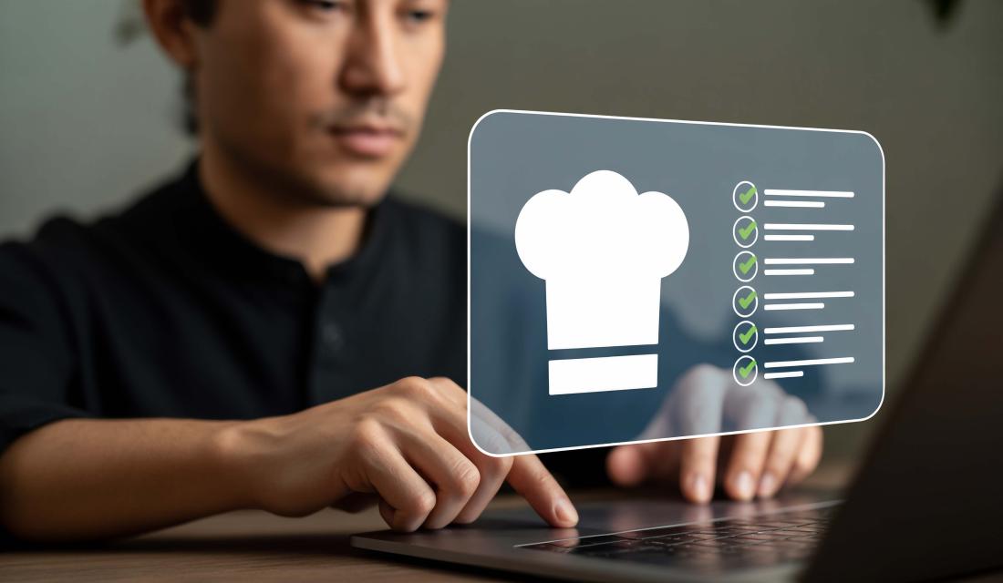 Ein konzentrierter Koch plant seine kulinarischen Kreationen akribisch anhand einer digitalen Checkliste auf einem modernen Laptop und verkörpert damit Präzision und Innovation in der Küche.