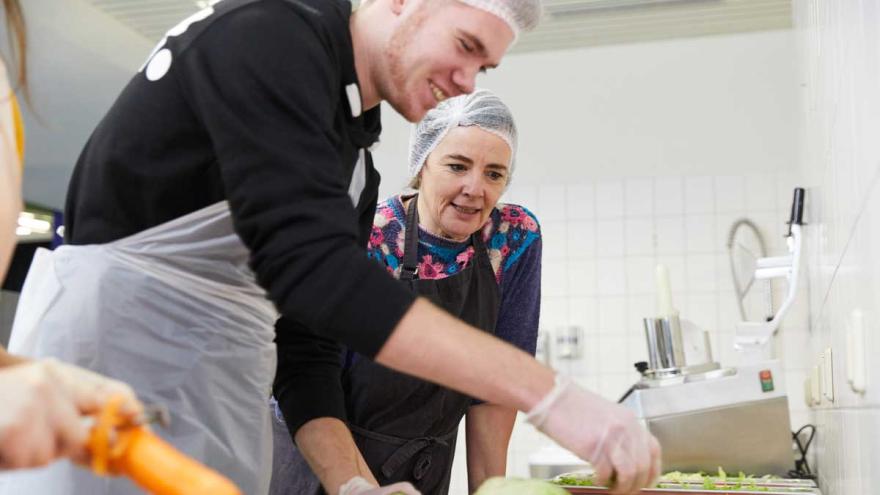 Ein Schüler und eine Frau bereiten Essen zu