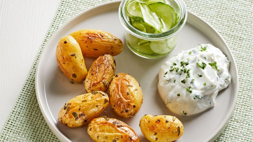 Kleine Ofenkartoffeln mit Kräuterquark und Gurkensalat auf einem Teller