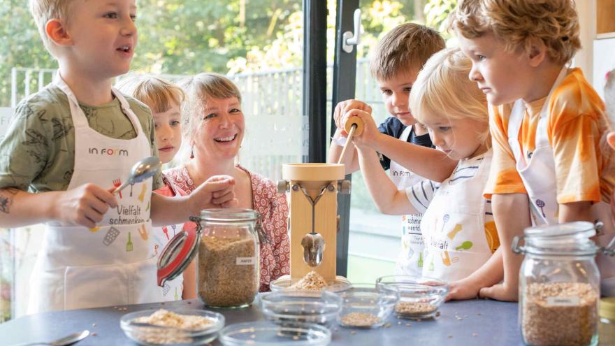 Kinder stehen am Tisch und experimentieren.