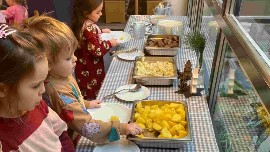 Kinder stehen am Mittagessens-Büffet und wählen aus.