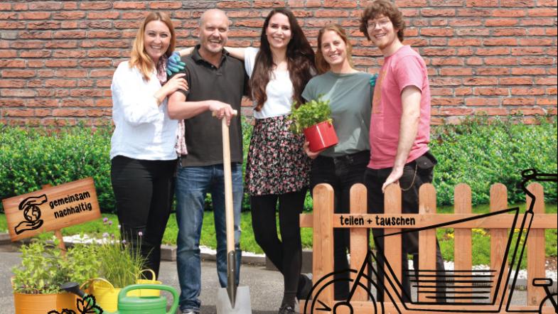 Drei Frauen und zwei Männer stehen hinter einem Gartenzaun und schauen in die Kamera.