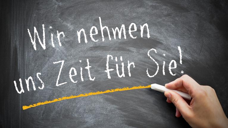 Schwarzer Tafelhintergrund mit den Worten Wir nehmen uns Zeit für Sie.